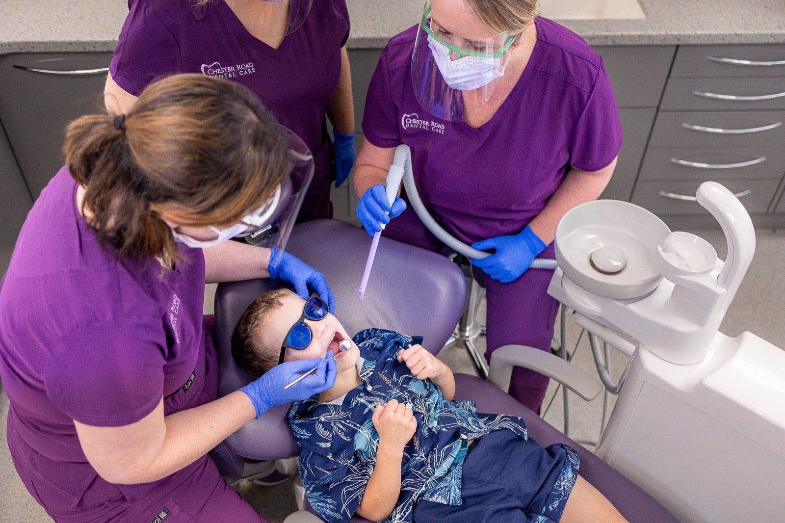 The dental team gently treating a young boy wearing tinted safety glasses