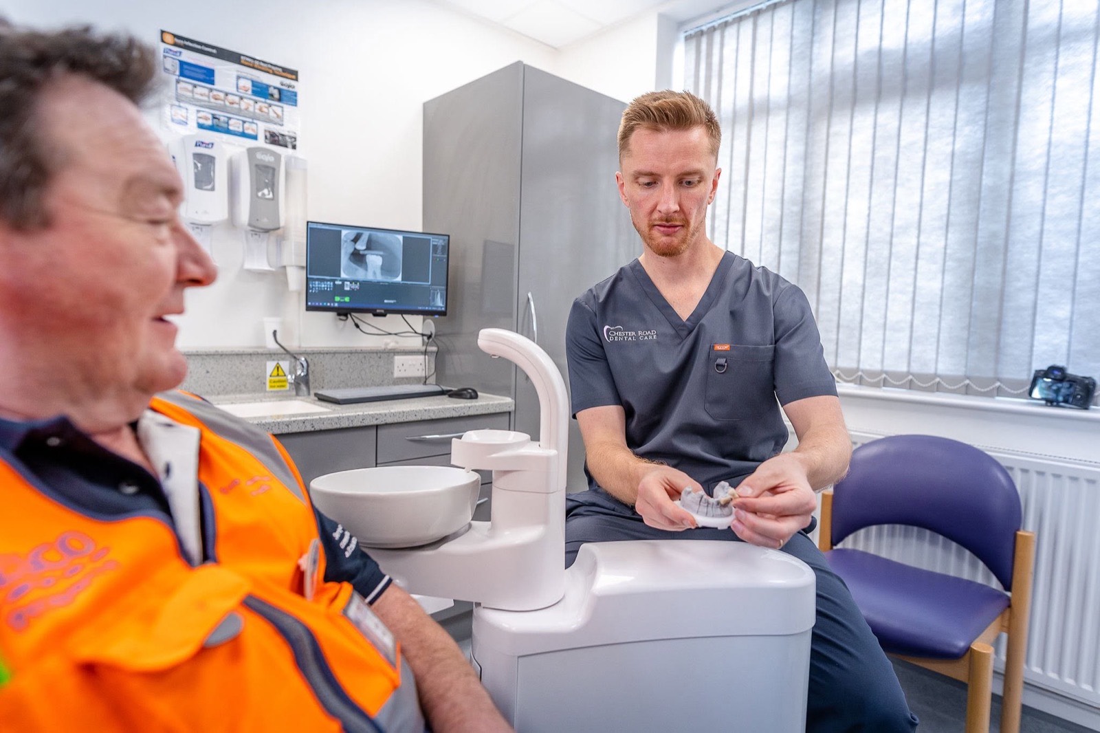 Dr John Young explaining treatment to a patient using a dental model in the surgery