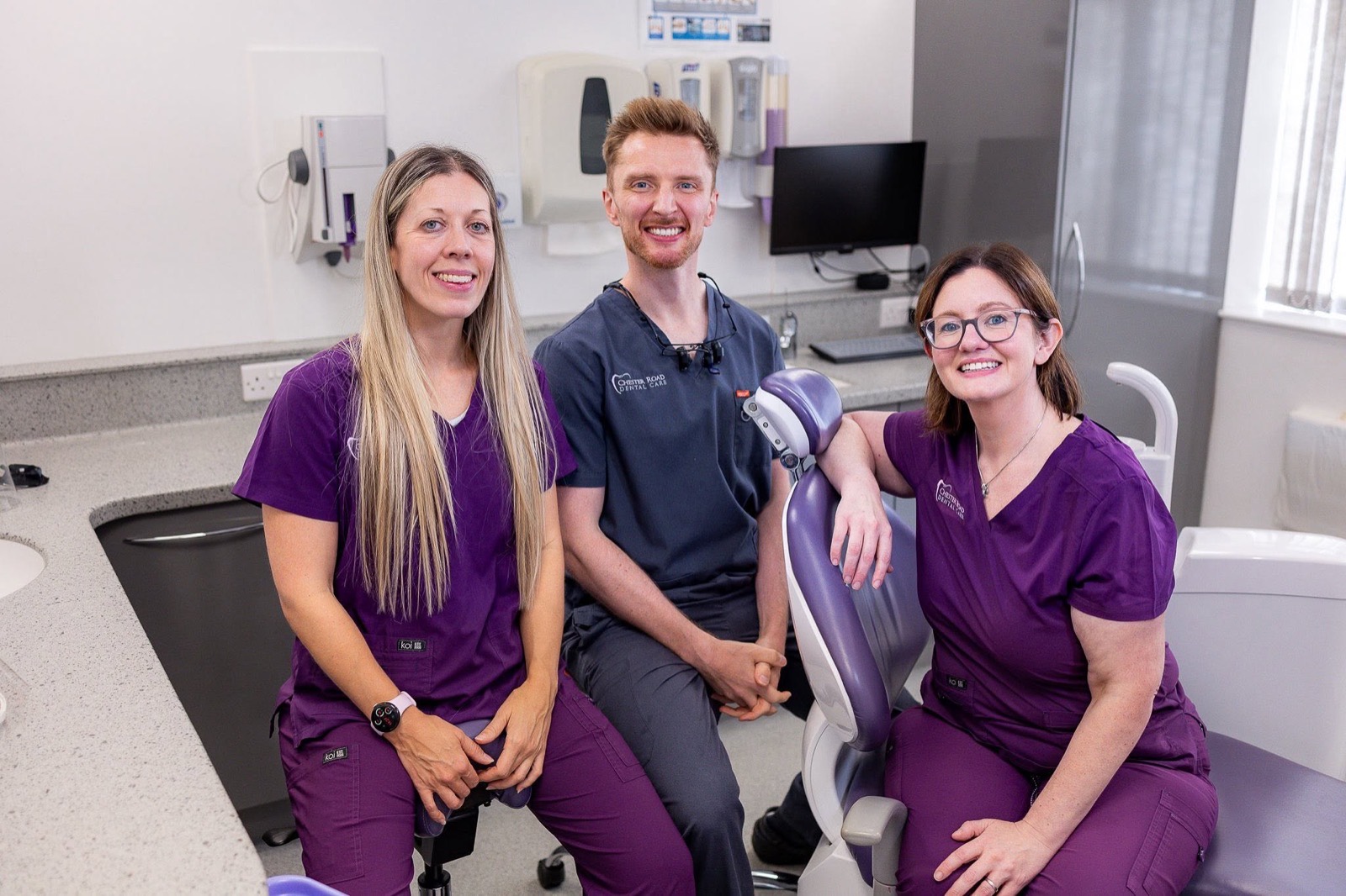 Dr Ella Woodward, Dr John Young and Dr Lisa-Marie Kitchen smiling together in a treatment room at Chester Road Dental Care