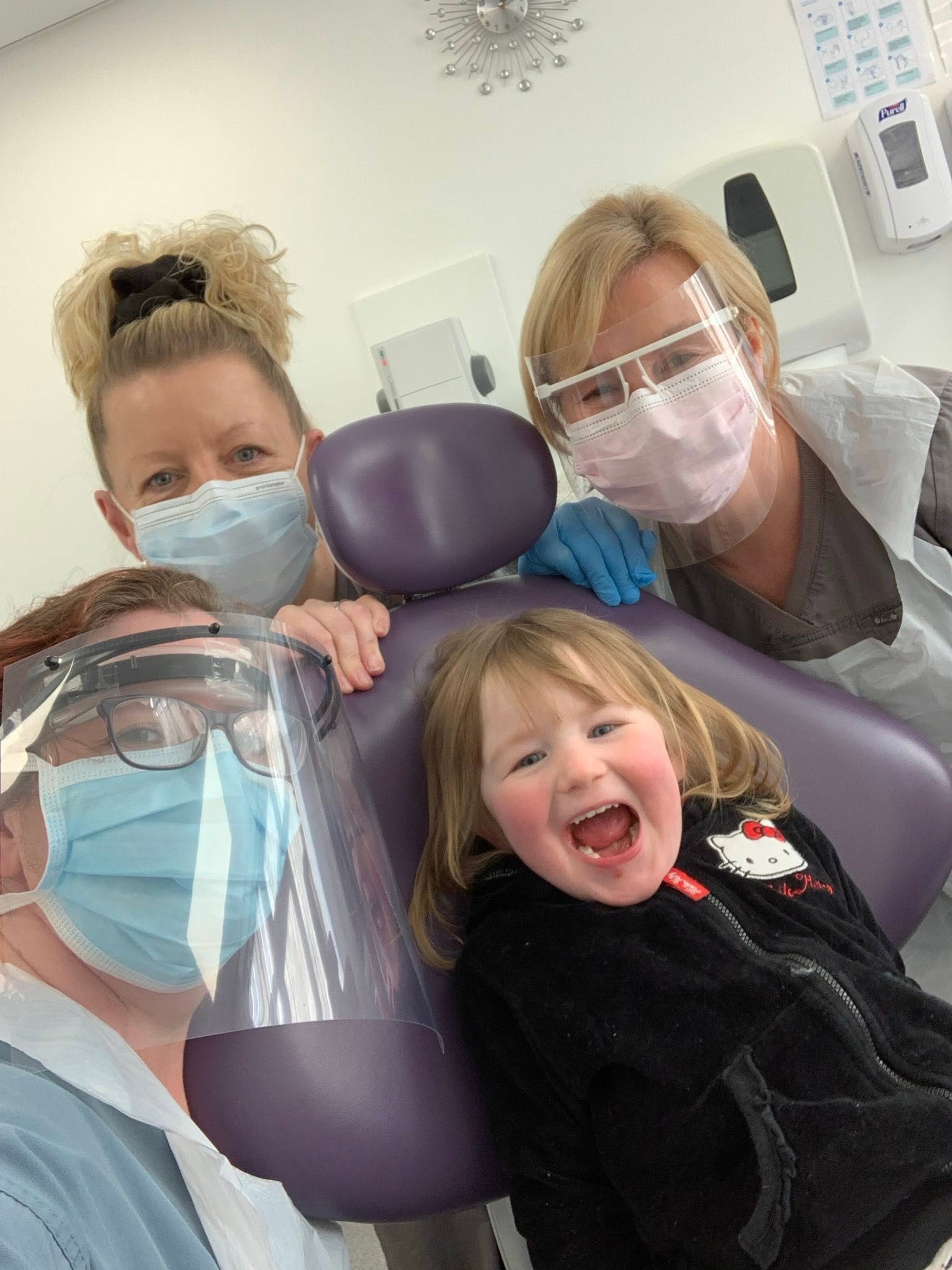 The full Chester Road Dental Care team gathered at the practice entrance in their purple scrubs