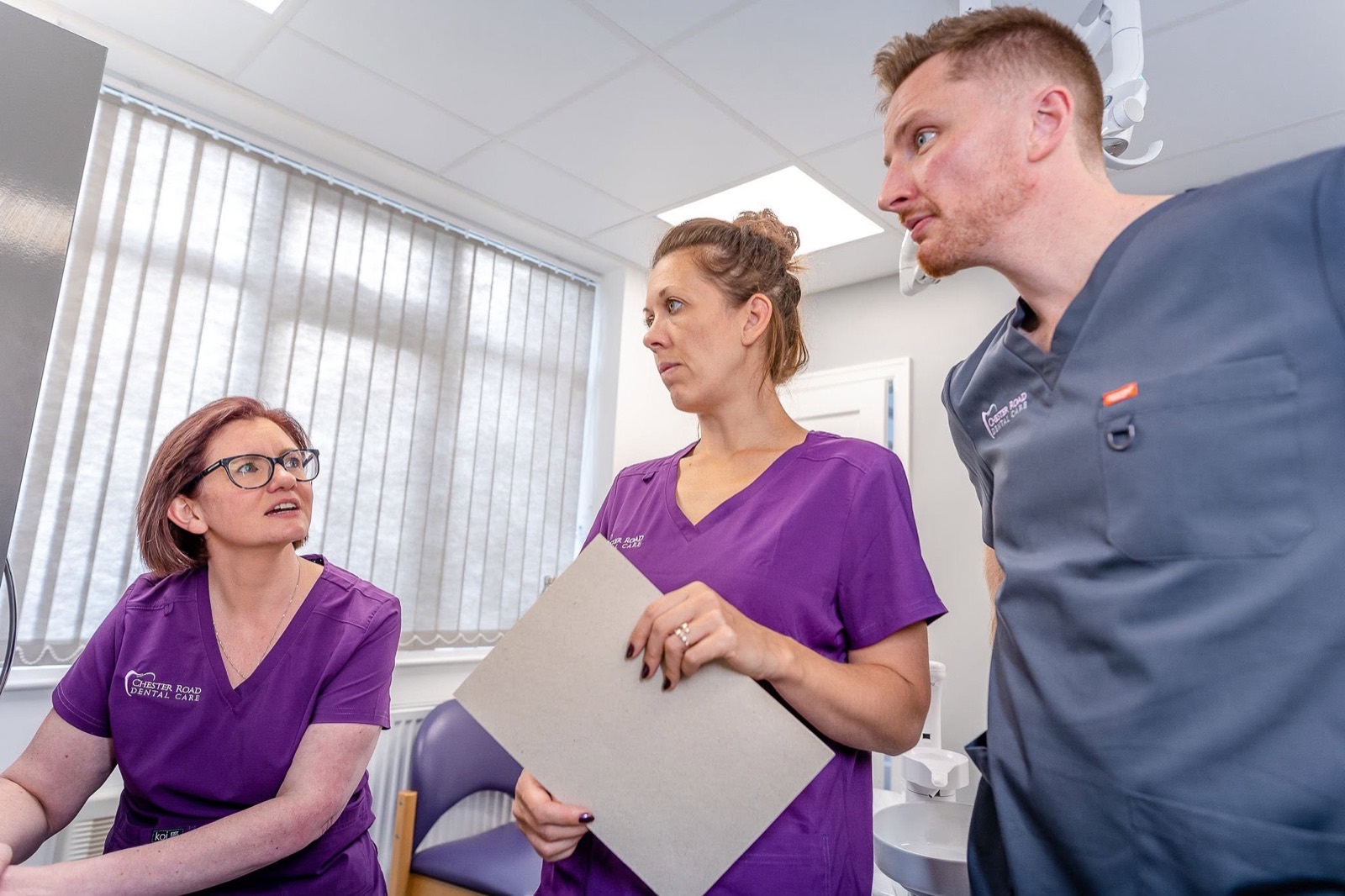 Dr John Young and dental nurses in discussion in the treatment room
