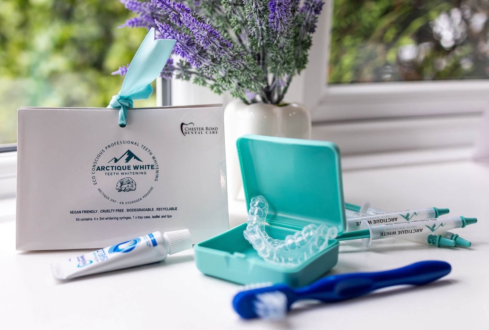 Arctique White professional teeth whitening kit with custom trays, case and whitening syringes on a windowsill